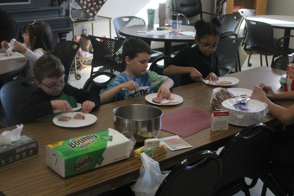 Luke, Carson and Lia work at cutting ham for all attendees at the Green Eggs and Ham Storytime at Lisbon Public Library and Southeast Linn Community Center Monday, March 11.