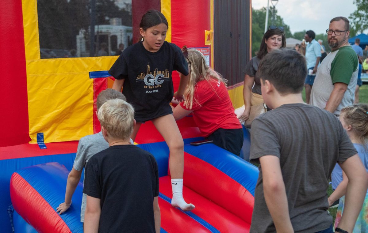 A kid exits the bouncy house as a line awaits their turn to enter the bouncing fun.