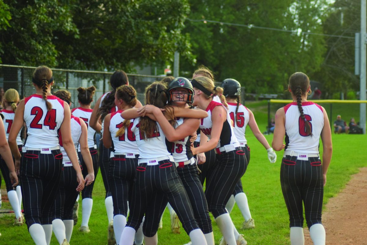 Lisbon sophomore Kamryn Kahl (13) gets a hug from Alexa Roos (12) as the entire team celebrates after hitting a two-run home run in the fifth inning Tuesday, July 23, in a Class 2A
regional final against Osage. Lisbon won, 4-2.