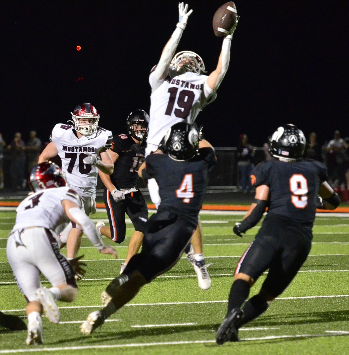 Cole Thurn (19) attempts a reception under pressure from Solon’s Maddox Kelley (4) and Owen Einwalter (9) Friday in Solon. 