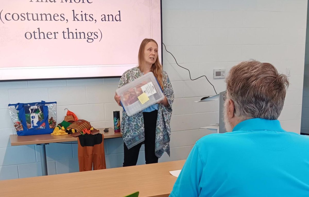 Lisbon Public Library director Elizabeth Hoover de Galvez holds up one of the resource kits available for libraries, collections of books for the book club. 