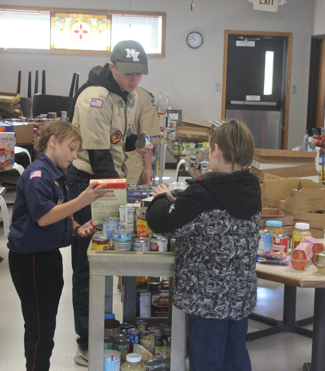 Scouts work at sorting a cart of donations to the proper donation areas for the food pantry to be shelved in the coming week.