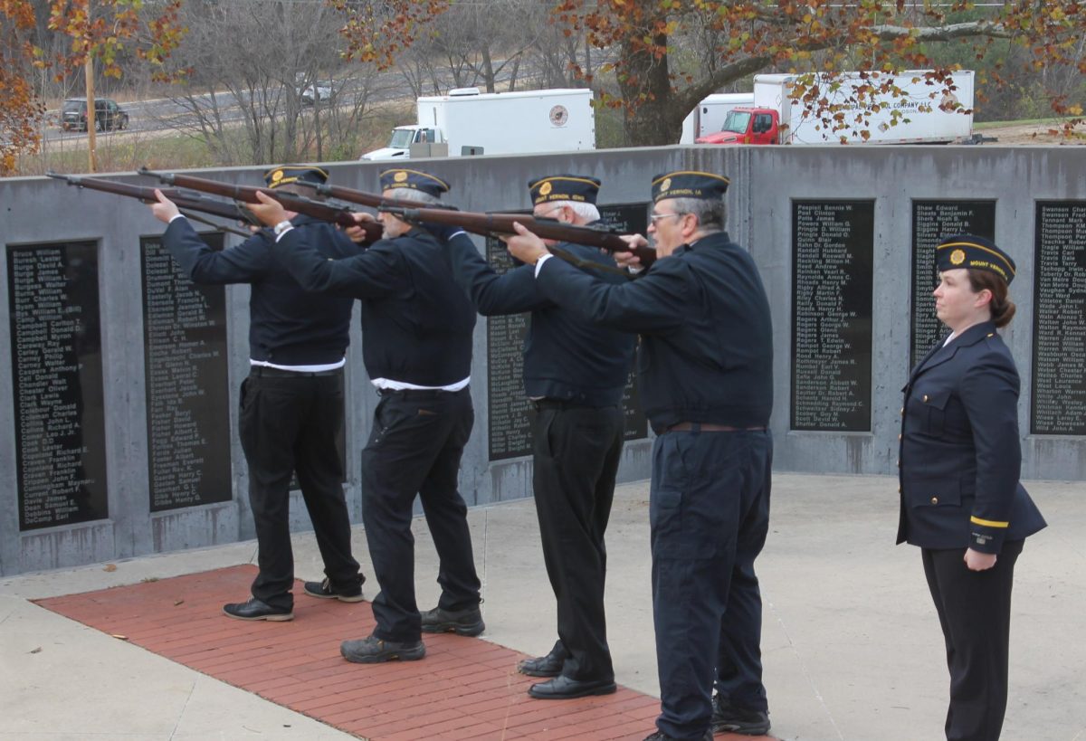 Legion members Kyle Earhart, Kevin Woods, Bob Meeker, Mike Woods fire a salute to veterans, with member Jade Helgens also present. 