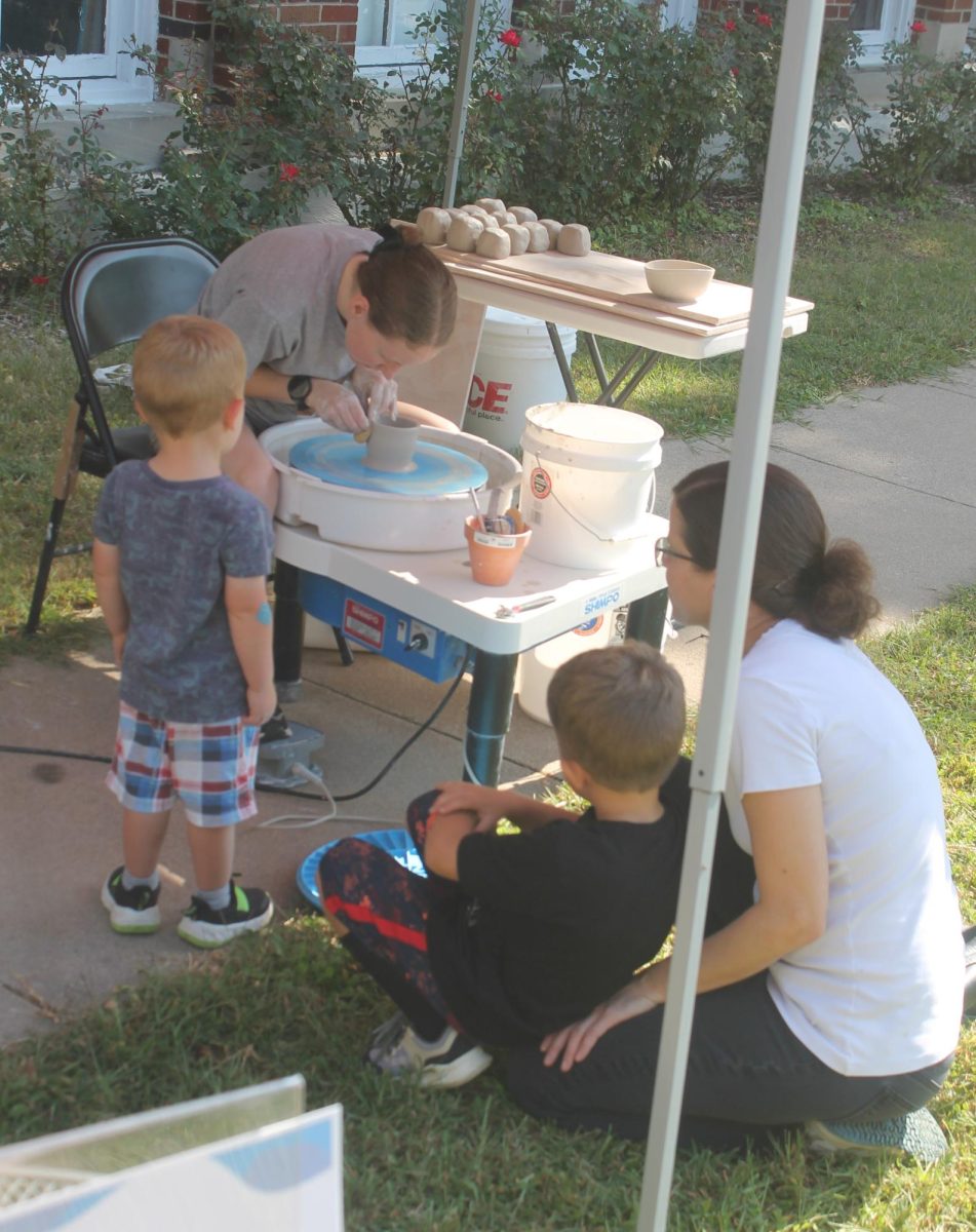 Hannah Walsh demonstrates how to use a Pottery wheel to children interested in how clay is used to make art.