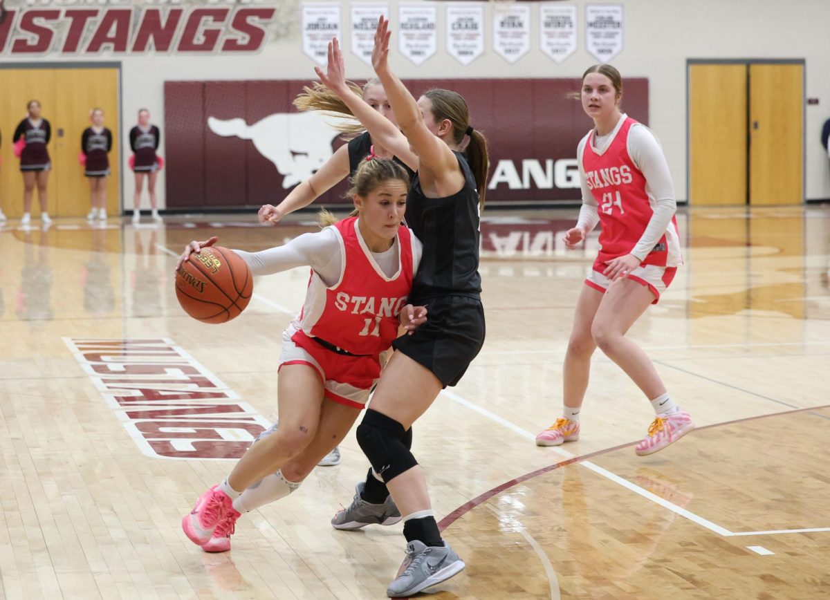 Mount Vernon’s Taylor Franck (No. 11) pushes the ball towards the hoop against a Center Point Urbana defender. (Kade Kaiser | Mustang Moon)