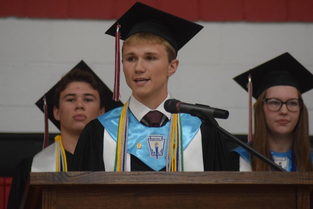 Caleb Ross gives his portion of the valedictorian speech with Jackson Knapp and Kaitlyn Silver over his shoulder.