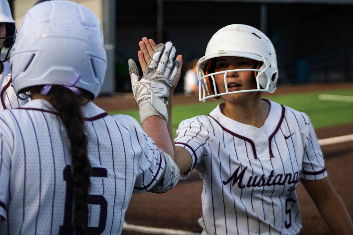Mount Vernon first baseman Sophia Patten congratulates second baseman Carly Elliot after she scores a run during the second game in a softball double header between the Mount Vernon Mustangs and the South Tama County Trojans at Van Metre Family Softball Complex in Mount Vernon on Monday, June 29, 2026.