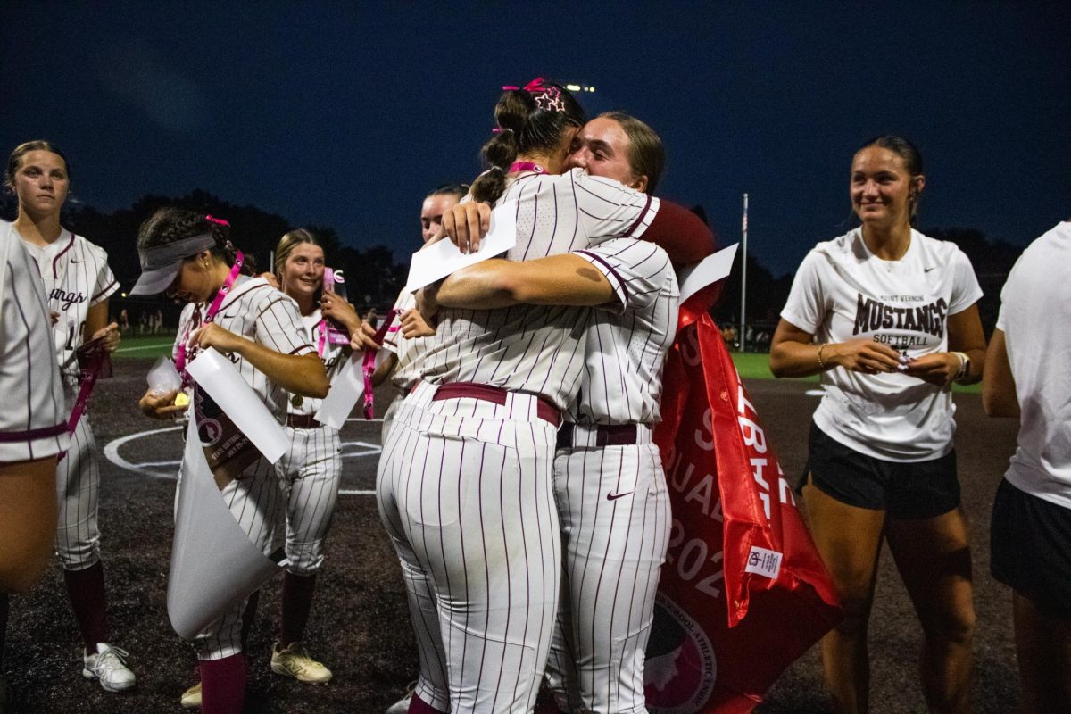 Mount Vernon pitcher Hayden Gookin hugs center fielder Kinley Nissen after receiving the Softball State Qualifier banner after a Class 3A Region 4 Championship softball match between the Mount Vernon Mustangs and the Center Point-Urbana Stormin Pointers at Van Metre Family Softball Field in Mount Vernon on Tuesday, July 14, 2026. The Mustangs beat the Stormin Pointers, 6-5.