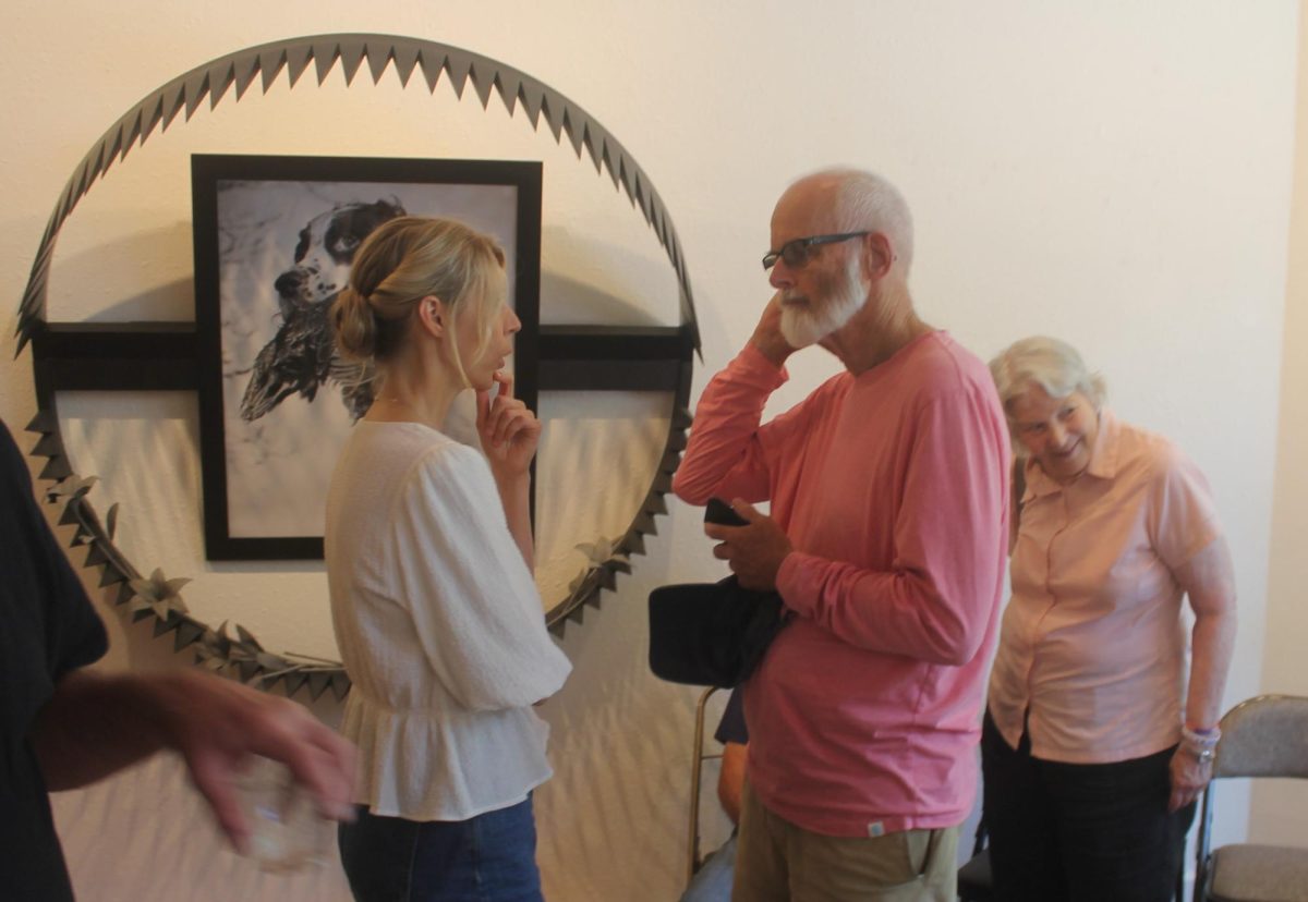 Christine Rebhuhn visits with Chris Carlson after the artist talk. One of Rebhuhn’s larger pieces is on the wall in the background.