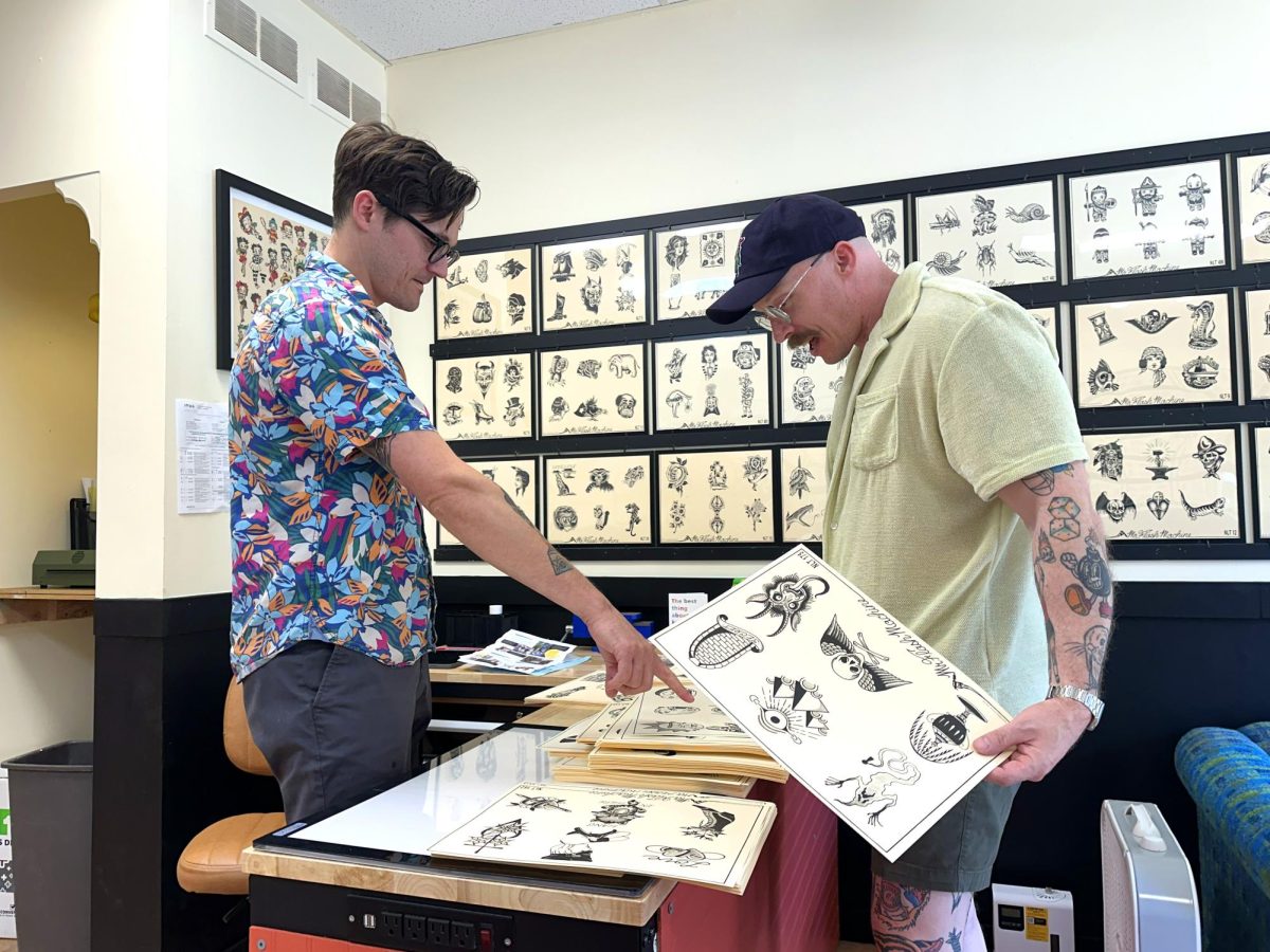  Chris Bostwick helps Nick Schueler, a client-turned-friend, pick out his next tattoo at Crispy Tattoo on June 22.